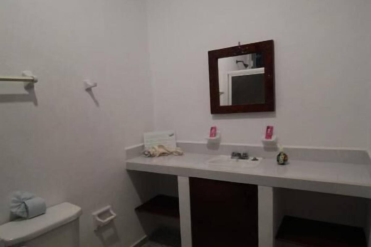 Casa de banho pequena e compacta, com sanita, lavatório e espelho.