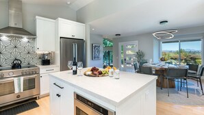 Een moderne keuken met een inbouw kookeiland, roestvrijstalen apparatuur en een eetgedeelte met uitzicht.