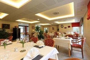 A dining area with multiple tables set for guests, featuring white tablecloths and red upholstered chairs. - Logis Hôtel Spa Rest. le Provence (Lanarce)