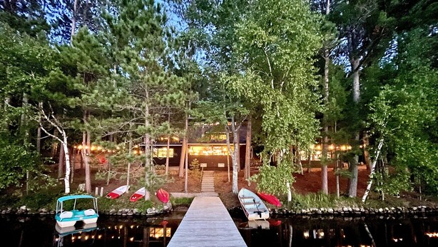 A wooden dock leading to a building surrounded by trees, with boats docked at the end. - Dollar Lake Retreat: Super Clean, Chef's Kitchen, Hot Tub + Amazing Sunsets (Eagle River)