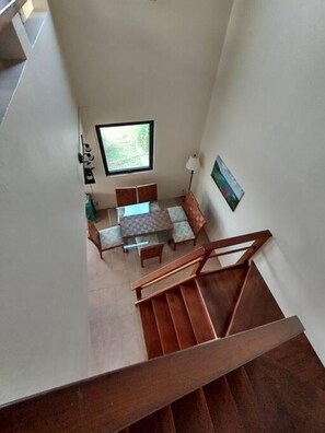 A staircase leading to a dining area with a table and chairs, a window, and a painting on the wall. - Sunset Ridge Villas Unit D (St. John)