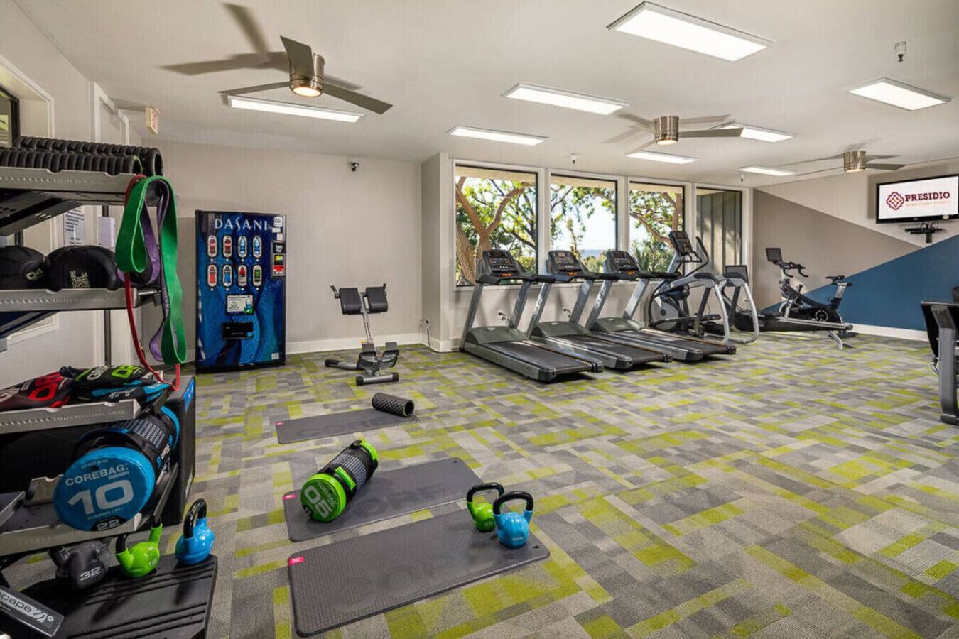 Une salle de sport équipée de tapis de course, de vélos d’exercice et de poids libres.