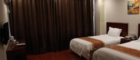 A hotel room with two beds, a desk, and a TV.