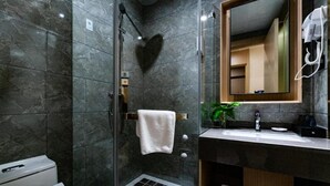 Ein modernes Badezimmer mit einer gläsernen Duschkabine, einem Waschtisch mit Spiegel und einer Toilette.