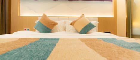 Una habitación de hotel con una cama, almohadas, una colcha y un cuadro en la pared.
