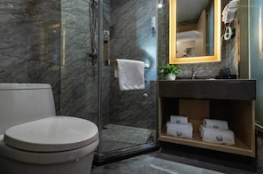 A modern bathroom with a glass-enclosed shower, a toilet, and a vanity with a mirror and towel rack.