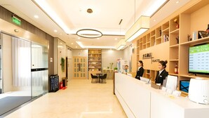 Ein Hotel-Empfangsbereich mit Empfangstresen, Sitzgelegenheiten und einer Bücherwand.
