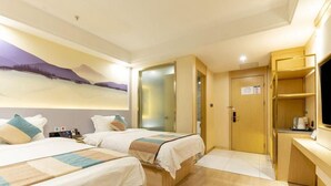 Ein Hotelzimmer mit zwei Betten, einem Schreibtisch, einem Fernseher und einer Tür zu einem Badezimmer.