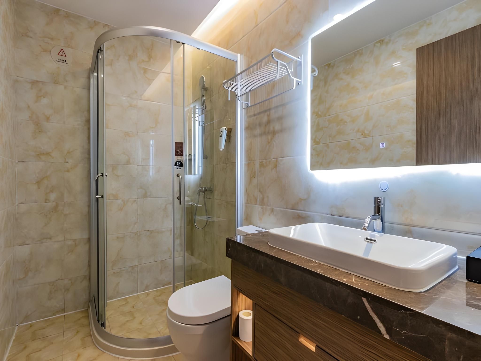 A modern bathroom with a glass-enclosed shower, a white sink, and a wooden vanity.