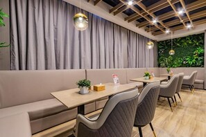 A modern restaurant interior with a long counter, cushioned seating, pendant lighting, and a green wall with plants. - Gya Jiaxing Haiyan County Changan Road Lishi Plaza Hotel (Jiaxing)