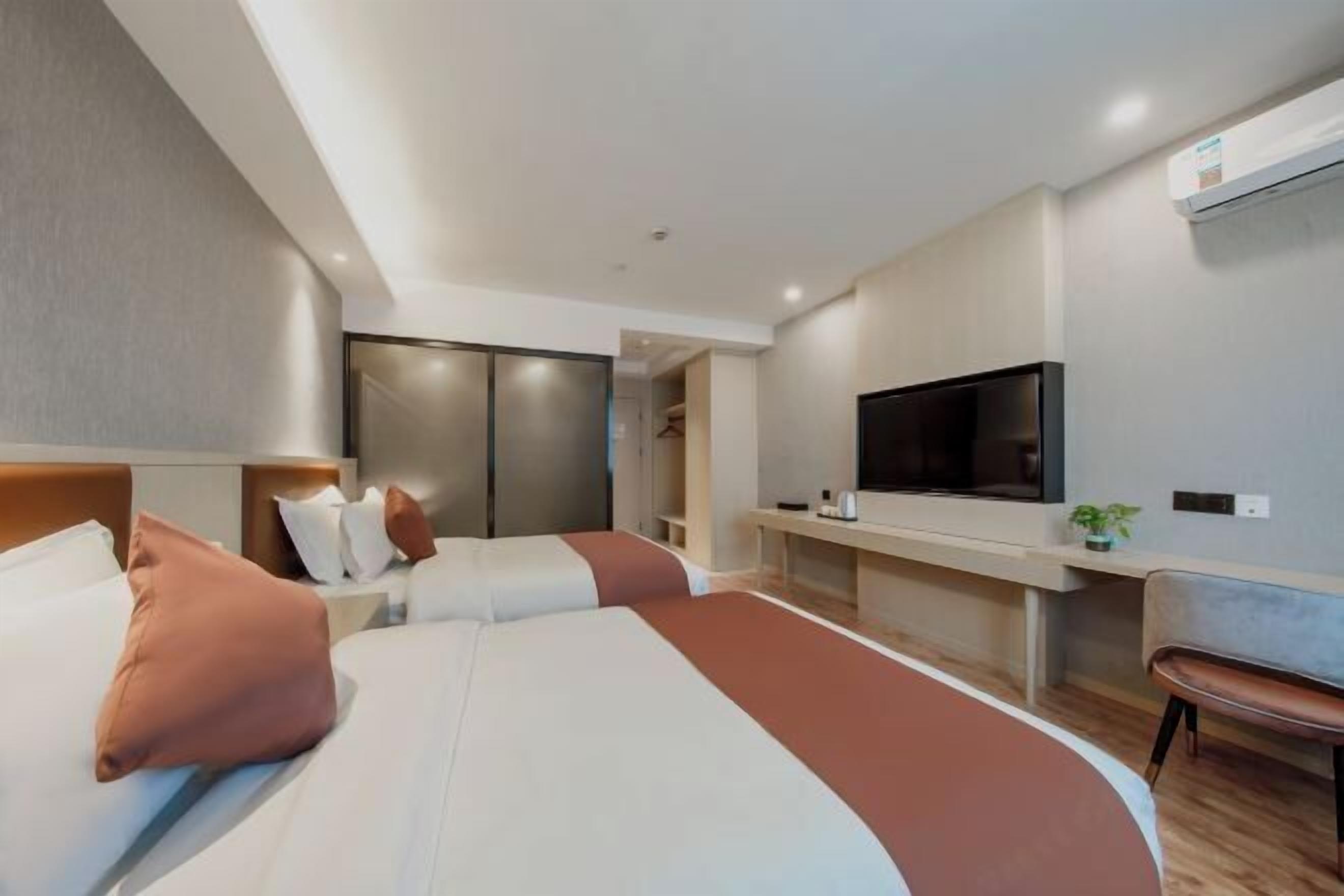 A modern hotel room with a large bed, a TV, a desk, and a chair.