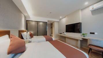 A modern hotel room with a large bed, a TV, a desk, and a chair.