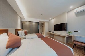 Ein modernes Hotelzimmer mit einem großen Bett, einem Fernseher, einem Schreibtisch und einem Sessel.
