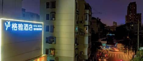 A hotel with a prominent sign, a street with vehicles, and buildings in the background.