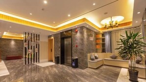 En moderne lobby med marmorgulv, en receptionsdisk, et loungeområde med sofaer og en stor potteplante.