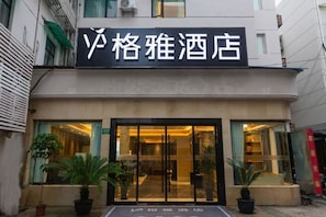 A hotel entrance with a sign, potted plants, and a glass door. - GYA Hotel (Shanghai Railway Station) (Shanghai)