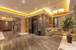A modern lobby with a marble floor, a reception desk, a seating area, and a large plant. - GYA Hotel (Shanghai Railway Station) (Shanghai)
