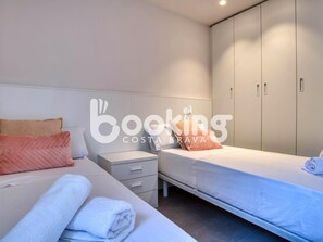 Una habitación de hotel con dos camas, una mesita de noche y un armario.