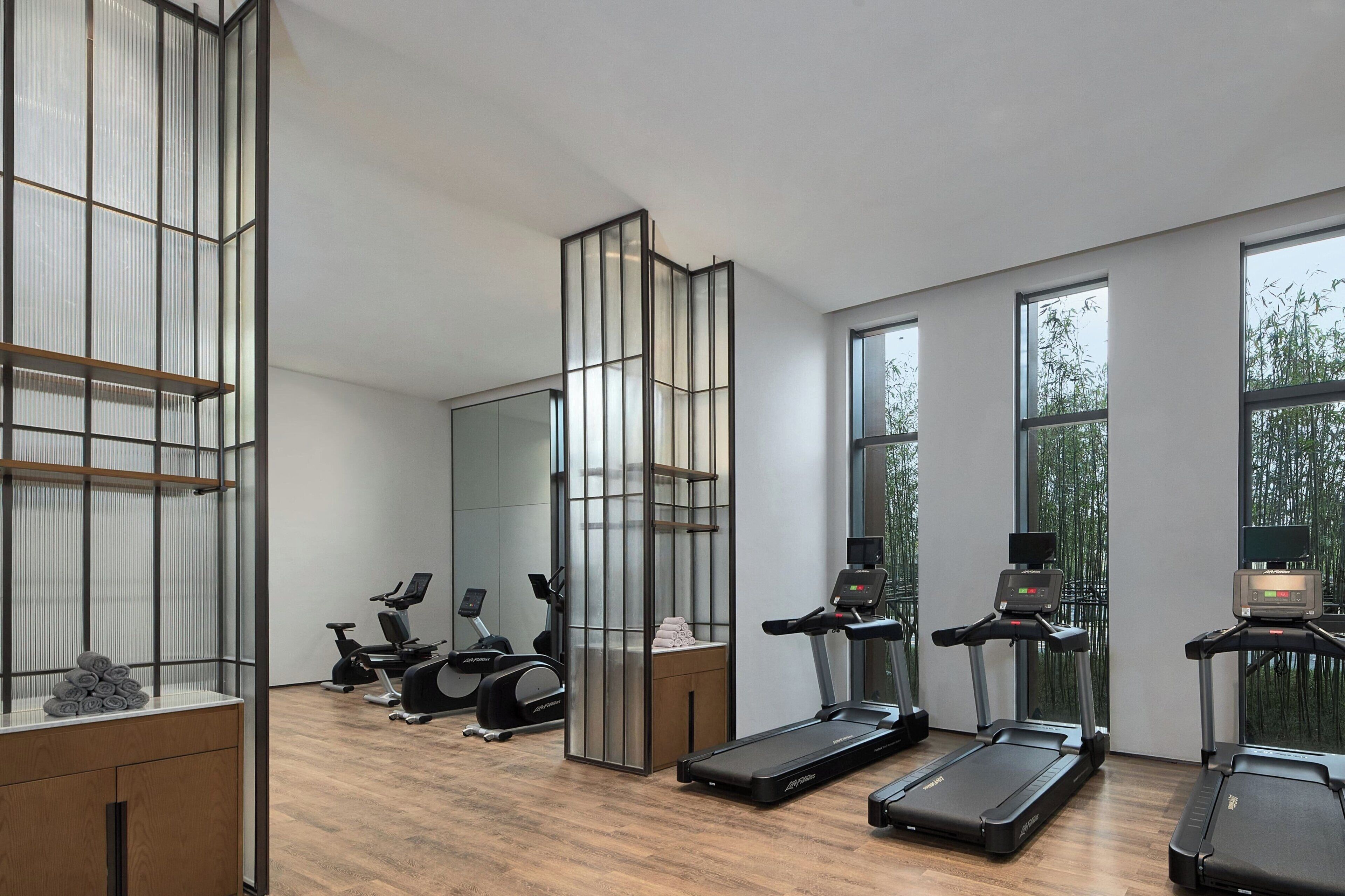 Ein modernes Fitnessstudio mit Laufbändern, Ergometer und einer Spiegelwand.