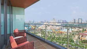 Ein Balkon mit Korbmöbeln, Blick auf die Stadt und ein Wasserpark im Hintergrund.