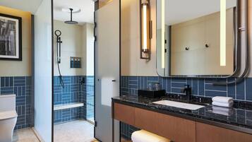 A modern bathroom with a glass shower enclosure, a marble countertop, and a large mirror.