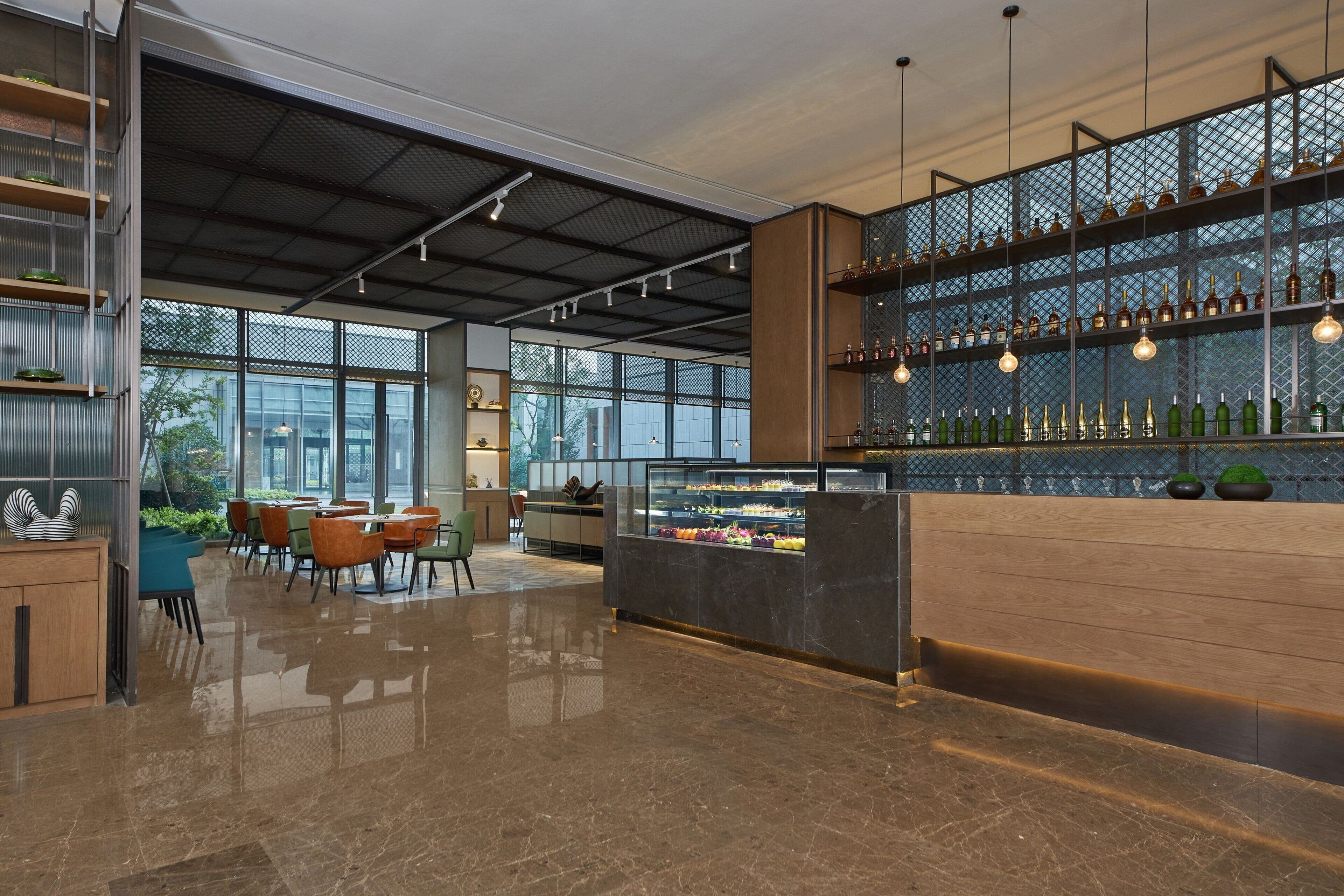 A spacious lobby with a bar area, seating, and a display case with food items.
