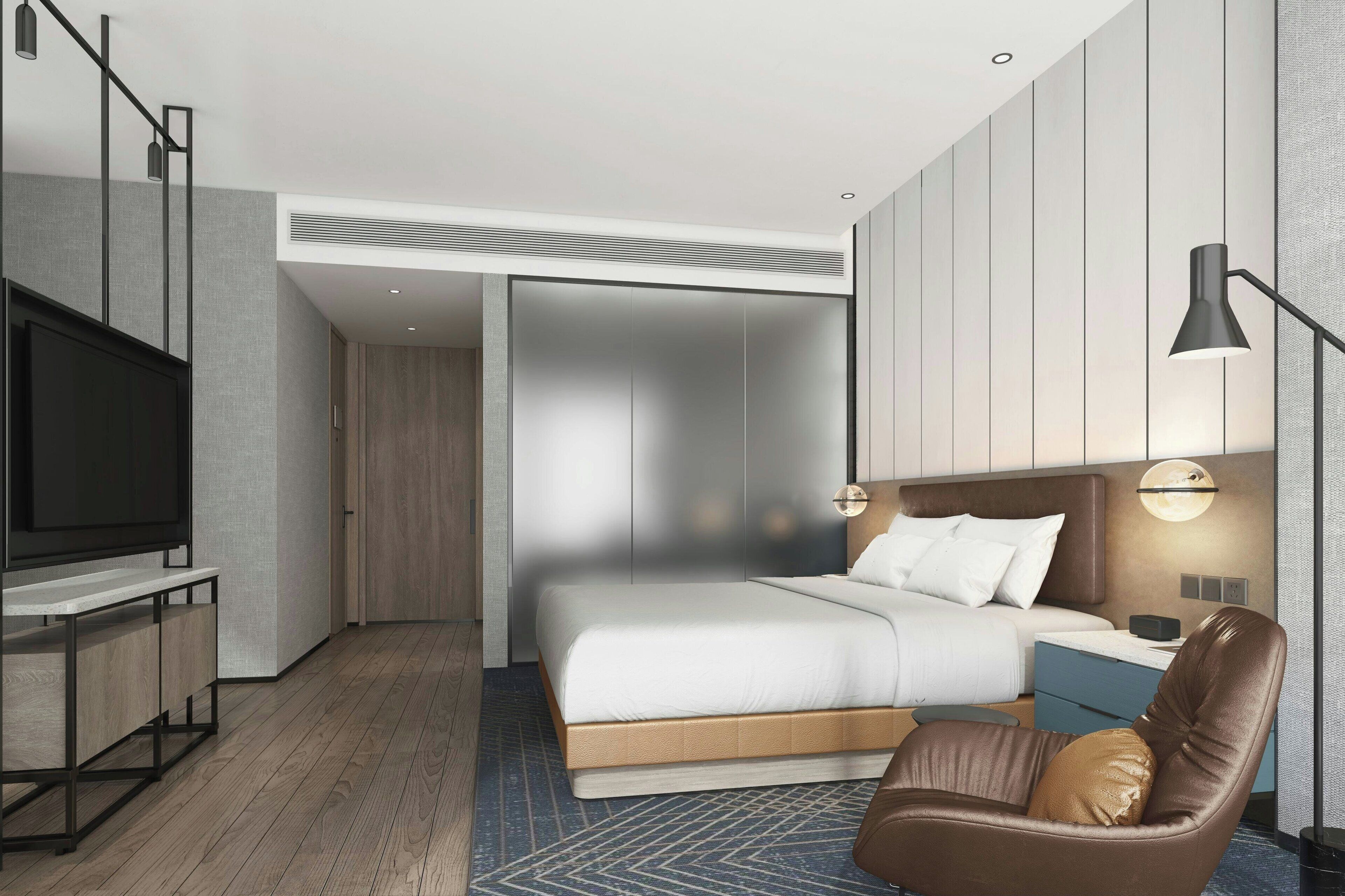 A modern hotel room with a large bed, a TV, a desk, and a chair.