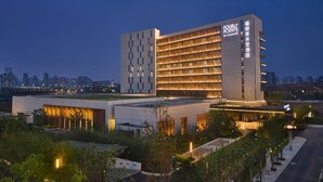 Ein modernes Hotel mit einem gut sichtbaren Schild 'Four Points by Sheraton', das ein mehrstöckiges Gebäude mit einer gemusterten Fassade und beleuchteten Fenstern zeigt.