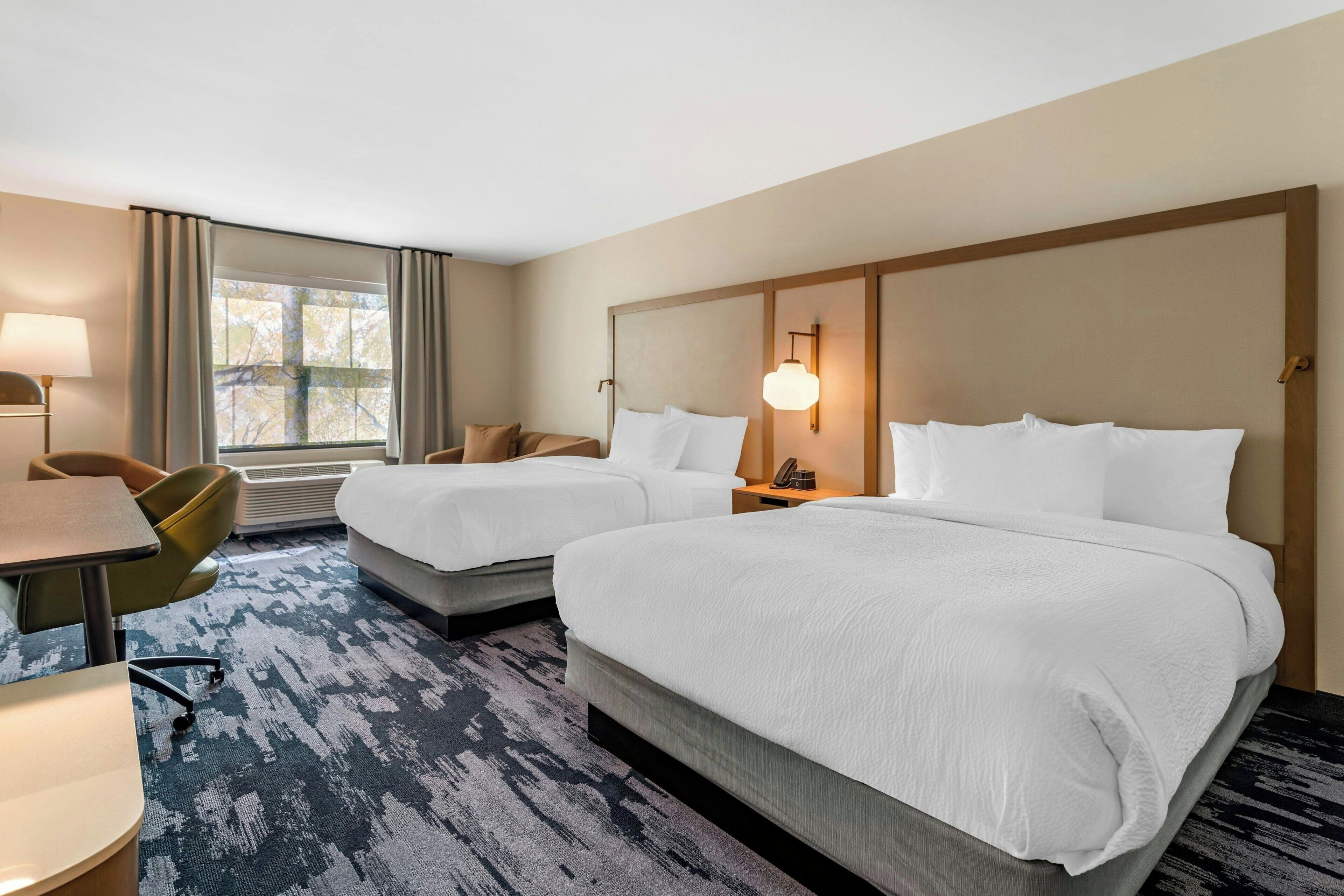 Une chambre d’hôtel avec deux lits, un bureau et une chaise.