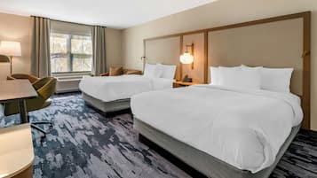Une chambre d’hôtel avec deux lits, un bureau et une chaise.