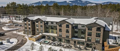 A multi-story hotel with a snow-covered roof and a pool area.