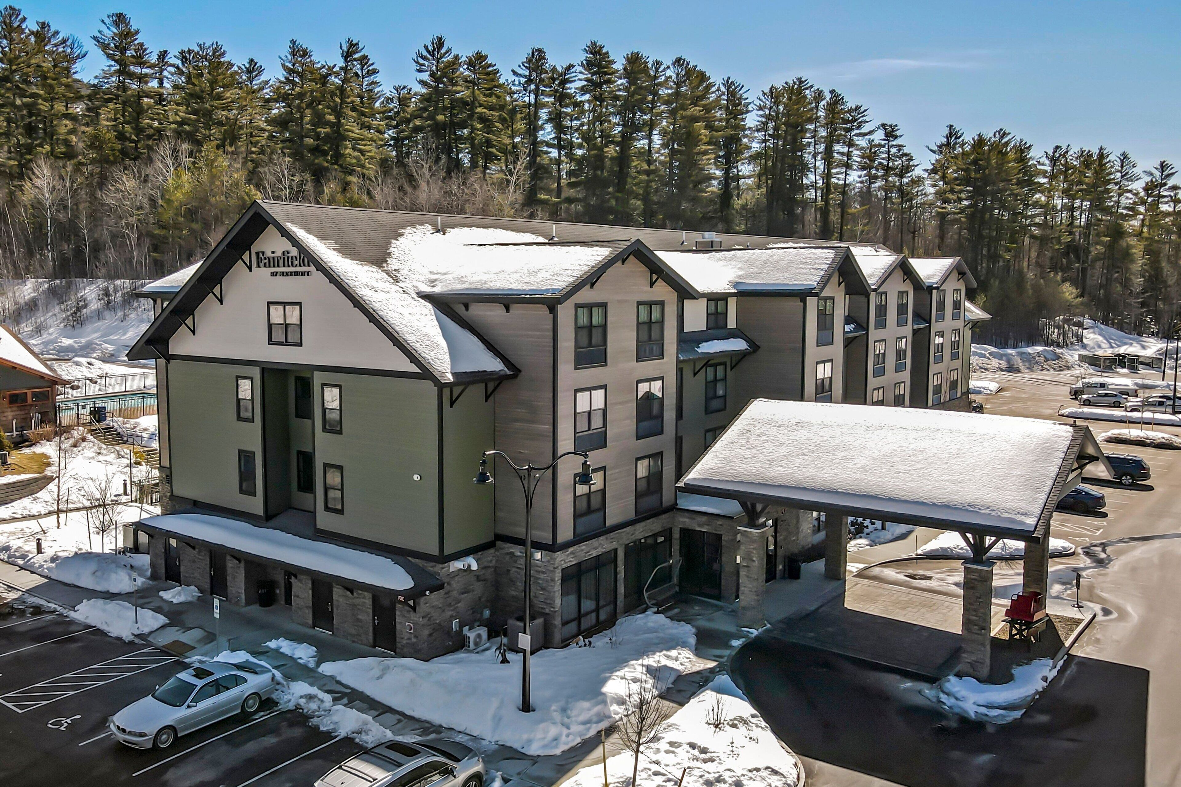 A multi-story hotel with a snow-covered roof and a covered outdoor area.