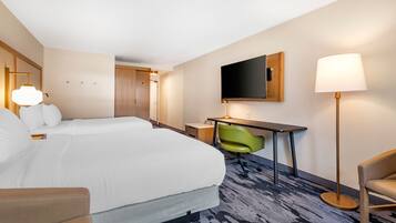 Een hotelkamer met een groot bed, een bureau, een stoel, een televisie en een lamp.