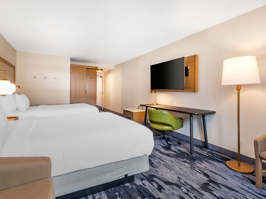 Een hotelkamer met een groot bed, een bureau, een stoel, een televisie en een lamp.