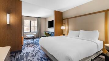 Une chambre d’hôtel avec un grand lit, un bureau, une chaise et un téléviseur.