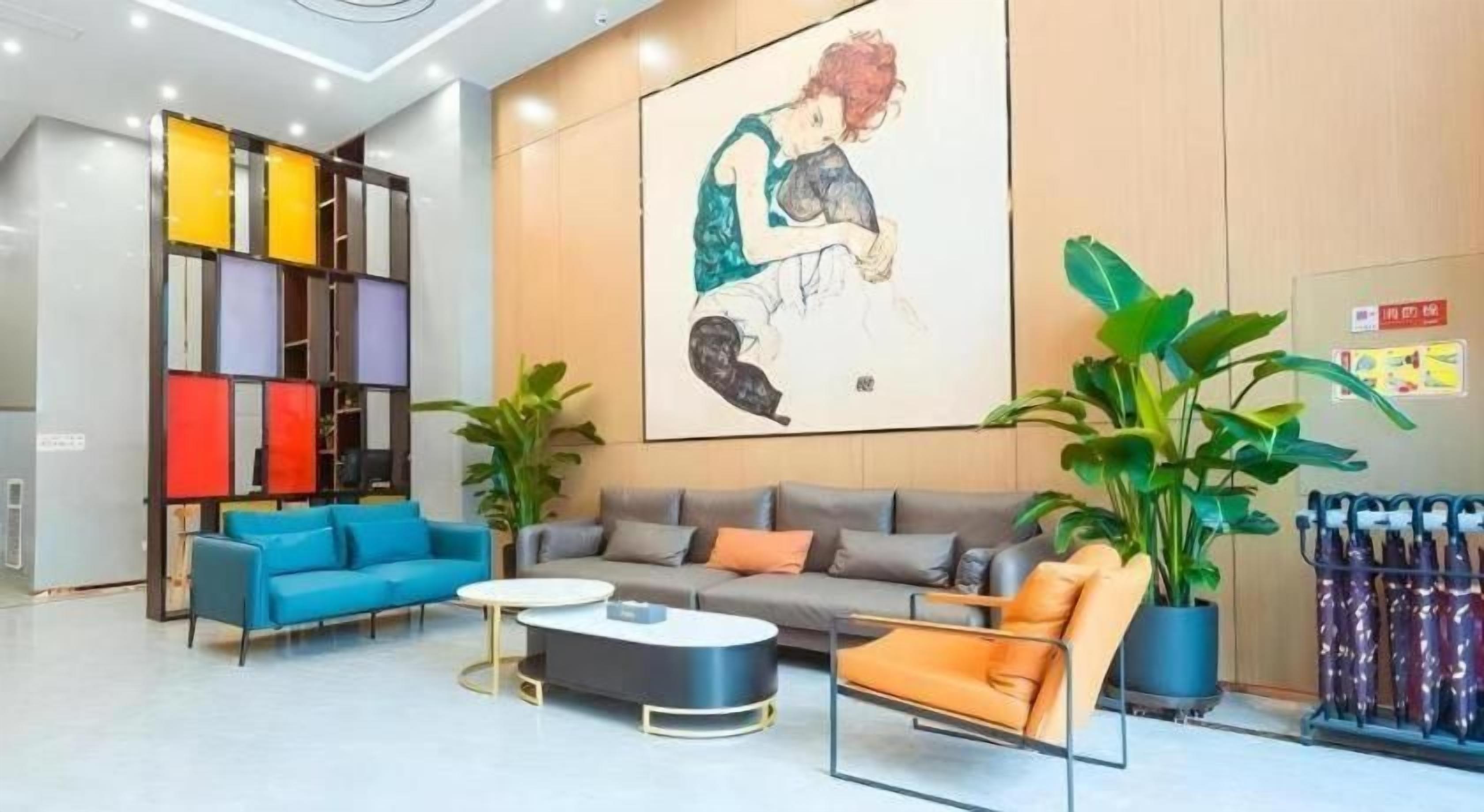 A modern hotel lobby with a sofa set, a coffee table, and a colorful wall unit.