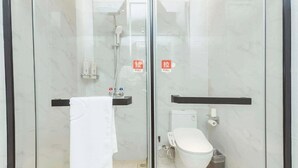 Un baño moderno con cabina de vidrio, inodoro blanco, ducha y toallero.