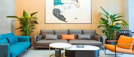 A modern living room with a sofa, two coffee tables, and a large abstract painting on the wall.