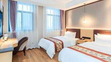 A hotel room with two beds, a desk, a chair, a phone, and a TV.
