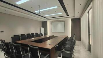 A conference room with a long table and chairs, a projector screen, and a large window.