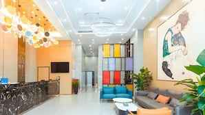 Un moderno vestíbulo de hotel con mostrador de recepción, zona de estar y decoración colorida.