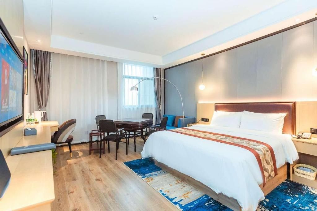 Una habitación de hotel con cama, escritorio, silla y televisor.