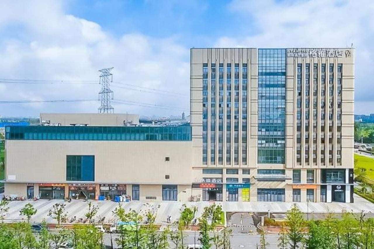 Un hôtel moderne doté d’une façade en verre remarquable, d’un toit plat et d’un pylône de ligne électrique bien visible en arrière-plan.
