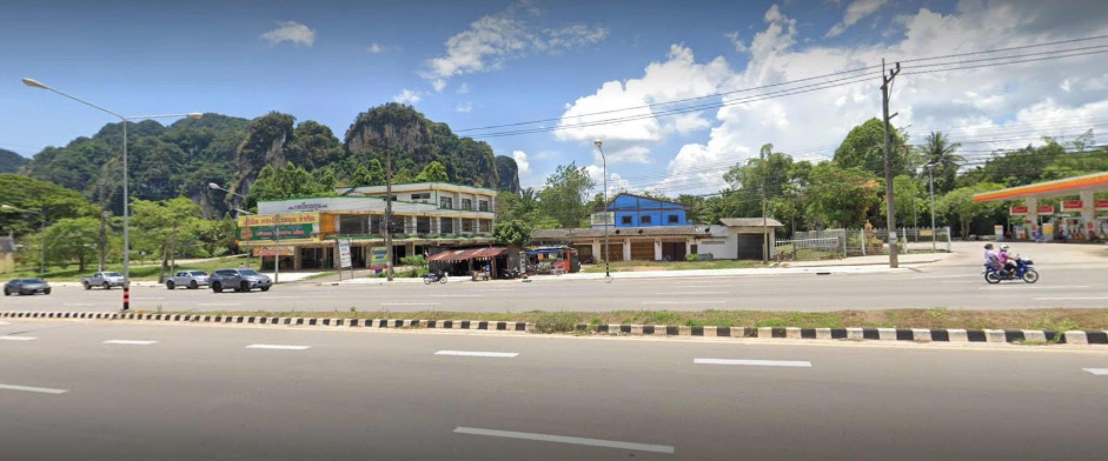 A street view with buildings, a gas station, and a mountain in the background.
