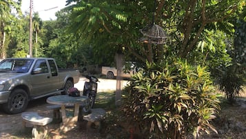 A pickup truck parked in a shaded area with a concrete table and benches.