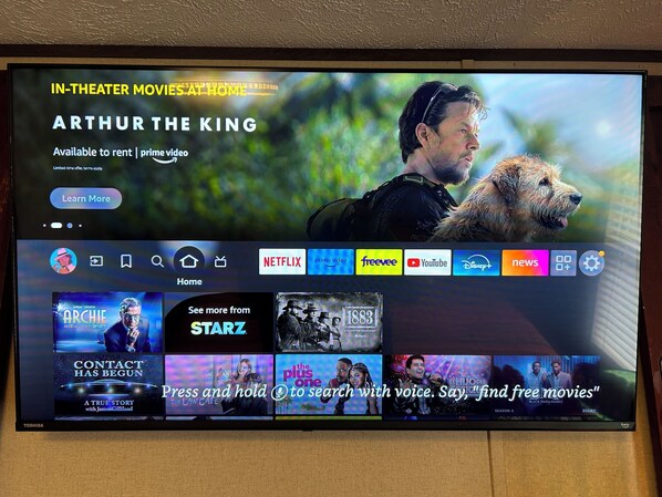 A television screen displaying a movie selection interface with options like 'Arthur the King' and 'Archie'.