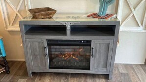 Una xemeneia amb porta de vidre, mantell de fusta i disseny rústic.