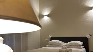 A neatly made bed with pillows and a rolled towel, a bedside table, and a lamp. - Domo Achenza (Terralba)