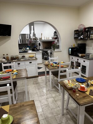 Une cuisine moderne avec des meubles blancs, un îlot central et un coin repas avec des chaises blanches.
