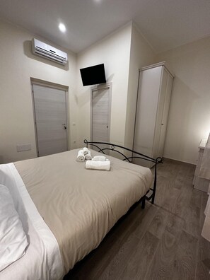 A bedroom with a bed, an air conditioning unit, a television, and a wardrobe. - Domo Achenza (Terralba)